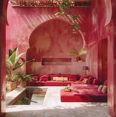 an outdoor living area with red couches and potted plants