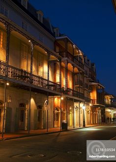 an empty city street at night with lights on the windows and balconies lit up