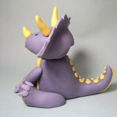 a purple toy with yellow horns sitting on the ground