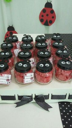 a table topped with lots of jars filled with red candies and ladybugs