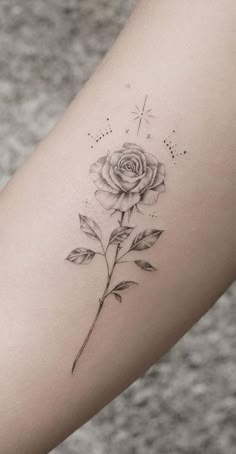 a black and white rose tattoo on the right arm, with stars in the background