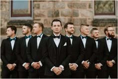 a group of men standing next to each other wearing black tuxedos and bow ties