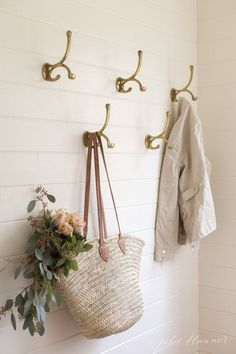 a white wall with two hooks and a purse hanging on it's hooks