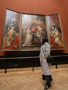 a woman standing in front of some paintings