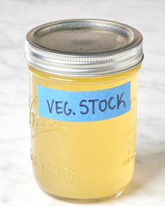 a glass jar filled with yellow liquid sitting on top of a white counter next to a blue sticker