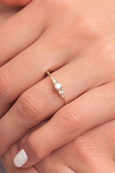 a woman's hand with a diamond ring on top of her finger and white nails