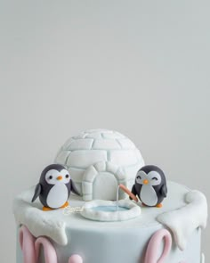 a cake decorated with penguins and an igloose