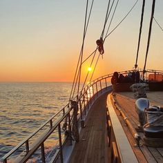 the sun is setting over the ocean on a boat