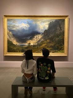 two people sitting on a bench in front of a painting