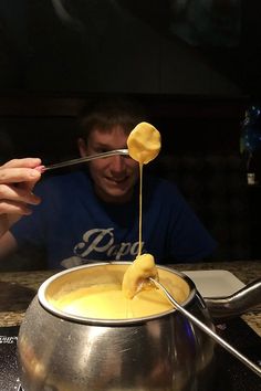 a man sitting at a table in front of a silver pot filled with food and spoons