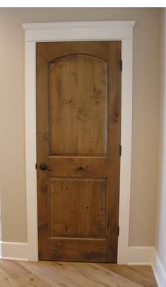 an empty room with a wooden door and hard wood floor