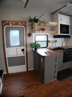 a small kitchen and living room in a trailer or camper with wood flooring