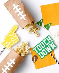 some brown paper bags filled with popcorn on top of a white table next to other items