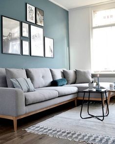 a living room with blue walls and pictures on the wall above the sectional couch,