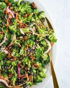 a white plate topped with broccoli and onions next to a gold fork on top of a table