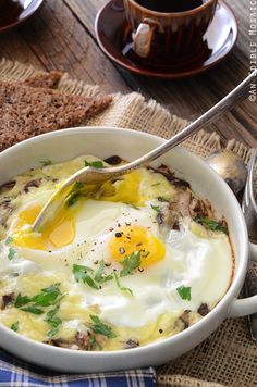 an egg is being cooked in a bowl with bread on the table next to it