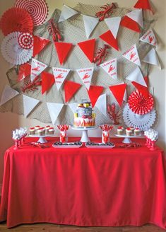 a table topped with red and white desserts next to a wall covered in paper fans