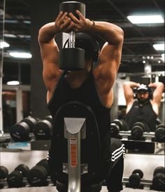 a man is doing exercises on a machine in the gym with his hands behind his head