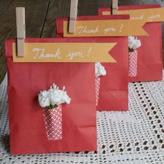 three bags with flowers on them are sitting on a doily and have thank you tags attached to them