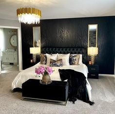 a black and white bedroom with chandelier, bed, nightstands and mirror