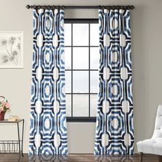 blue and white curtains with circles on them in front of a window, next to a chair