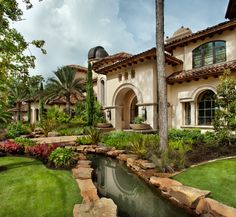 a house with a pond in front of it and landscaping around the pool is shown