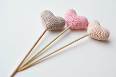 three crocheted heart shaped lollipops with wooden sticks sticking out of them