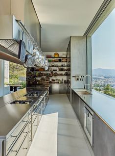 a kitchen with stainless steel appliances and open shelving on the wall, overlooking a city