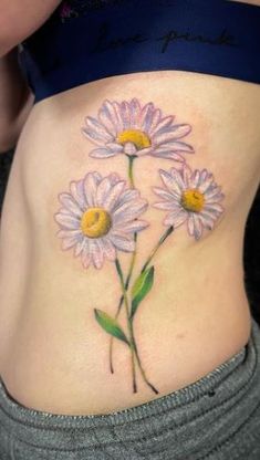 a woman's stomach with three daisies on her belly and one flower in the middle