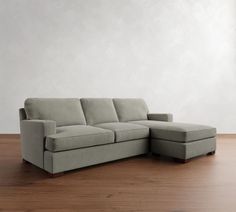 a gray couch sitting on top of a hard wood floor next to a white wall