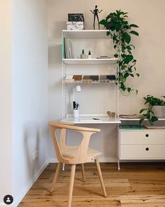 a white desk and chair in a room with wooden floors, bookshelves and plants