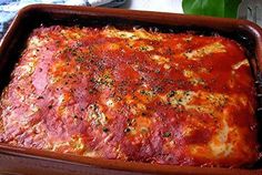 a casserole dish with meat and cheese in it on a table next to utensils