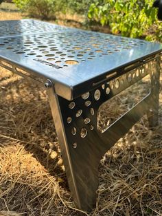 a metal table sitting on top of dry grass