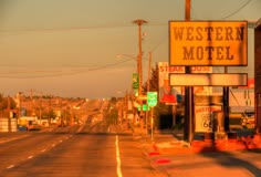 an old western motel sign on the side of a road