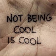 a hand with writing on it that says not being cool is cool