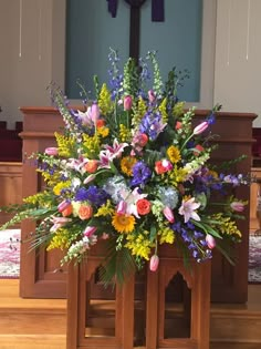 an arrangement of flowers is placed on the alter in front of a church pews