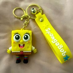 a yellow spongebob keychain sitting on top of a bed