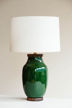 a green table lamp with a white shade on it