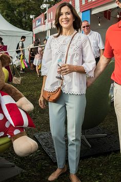 a woman standing next to a giant teddy bear in front of a tent with other people