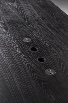 three black buttons are on the side of a wooden table with silver hardware and wood grained surface