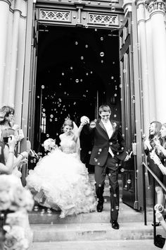 a bride and groom walking down the stairs with bubbles in their hand as they leave the church