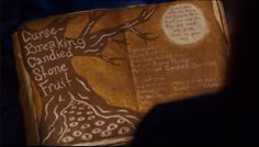 an open book with writing on it and a tree in the middle, next to a person's shadow