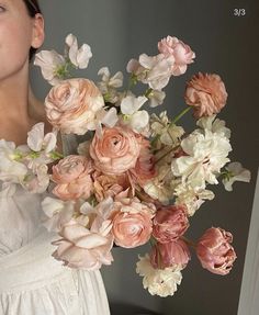 a woman holding a bouquet of flowers in front of her face and looking at the camera