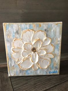 a white flower painted on top of a piece of wood