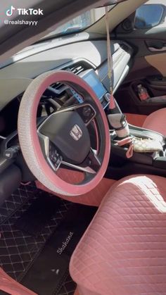 the interior of a car with pink leather seats and steering wheel, including an electronic device