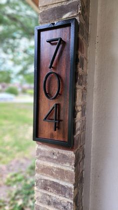 a house number sign mounted to the side of a brick building with grass in the background