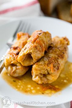 a white plate topped with chicken covered in gravy next to a slice of bread