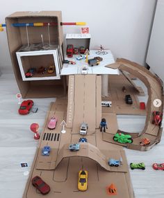 toy cars and trucks are parked on the floor in front of a model car track