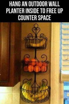 two metal baskets filled with fruit sitting on top of a counter next to a window