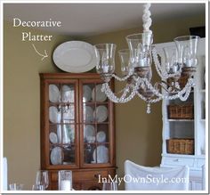 a chandelier hanging over a dining room table with plates and glasses on it